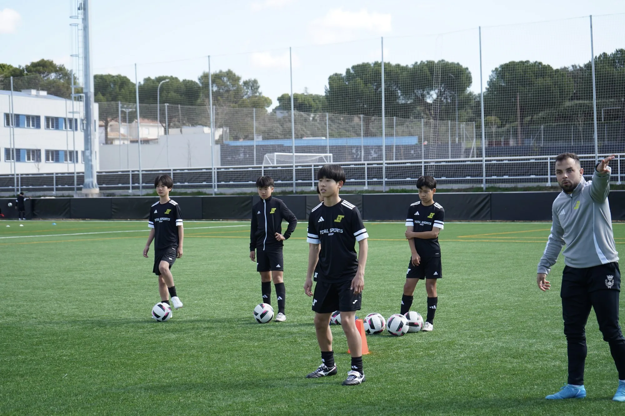 A coach giving instructions to players around the ball in training