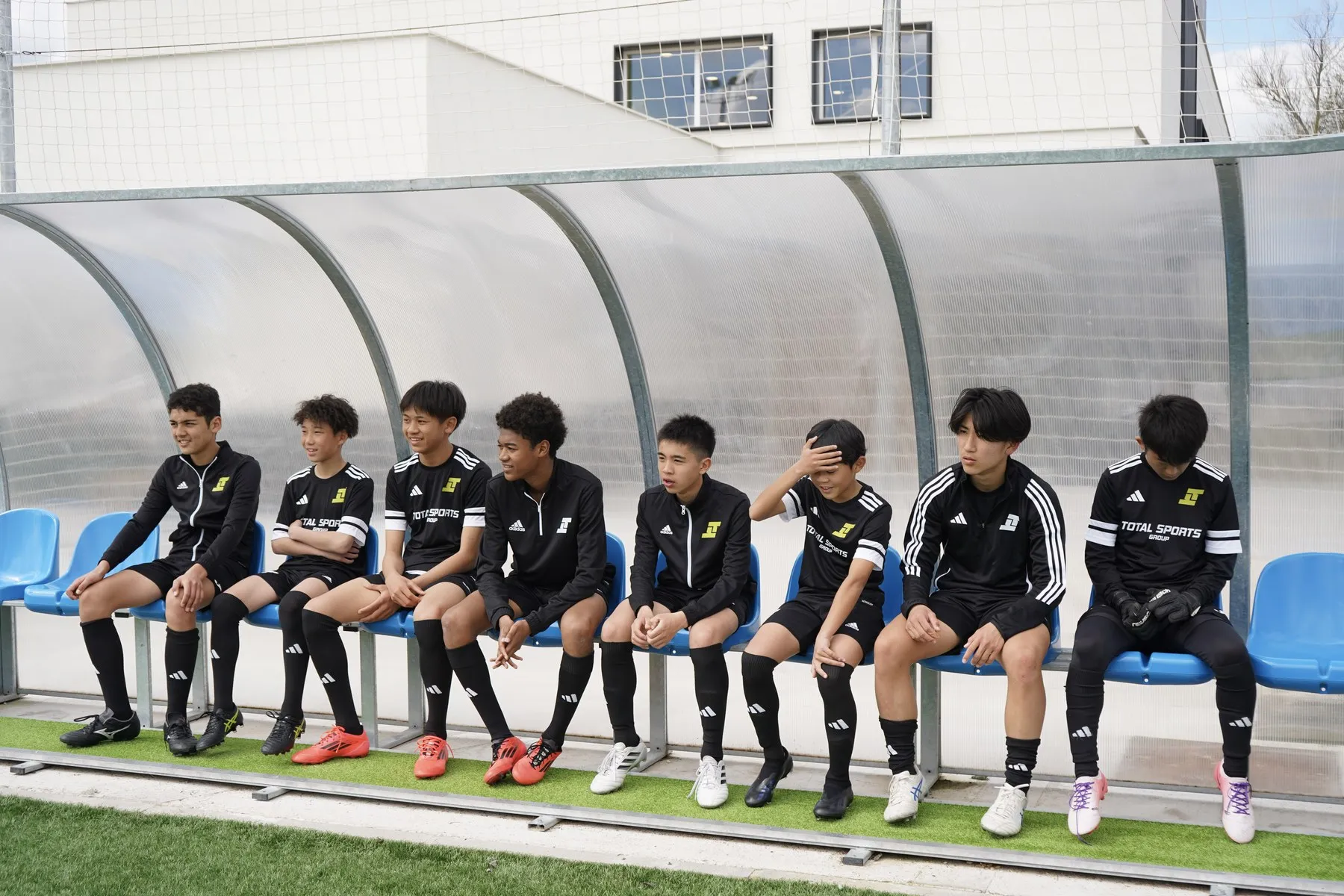 The squad sitting together on the bench beside the pitch
