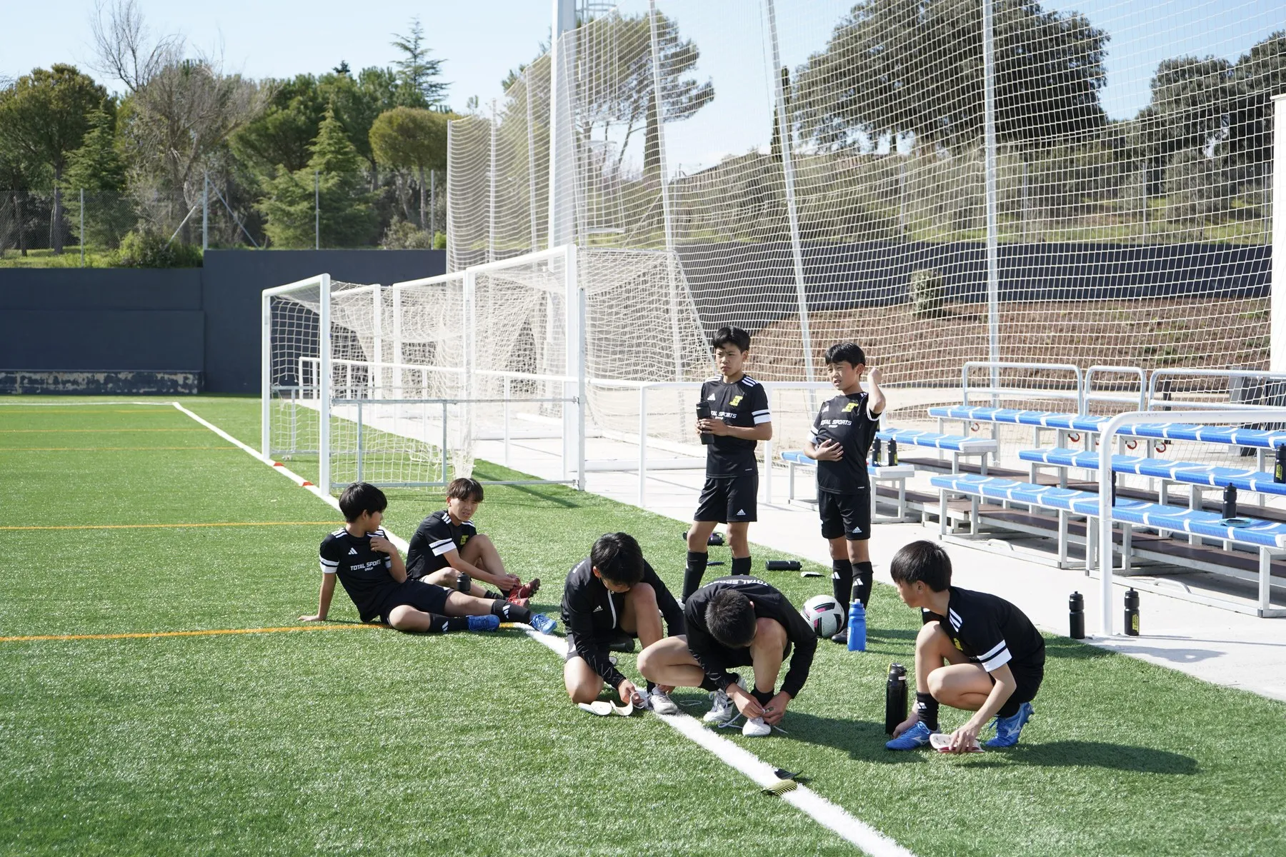 Players resting and changing their boots at the side of the campus pitch